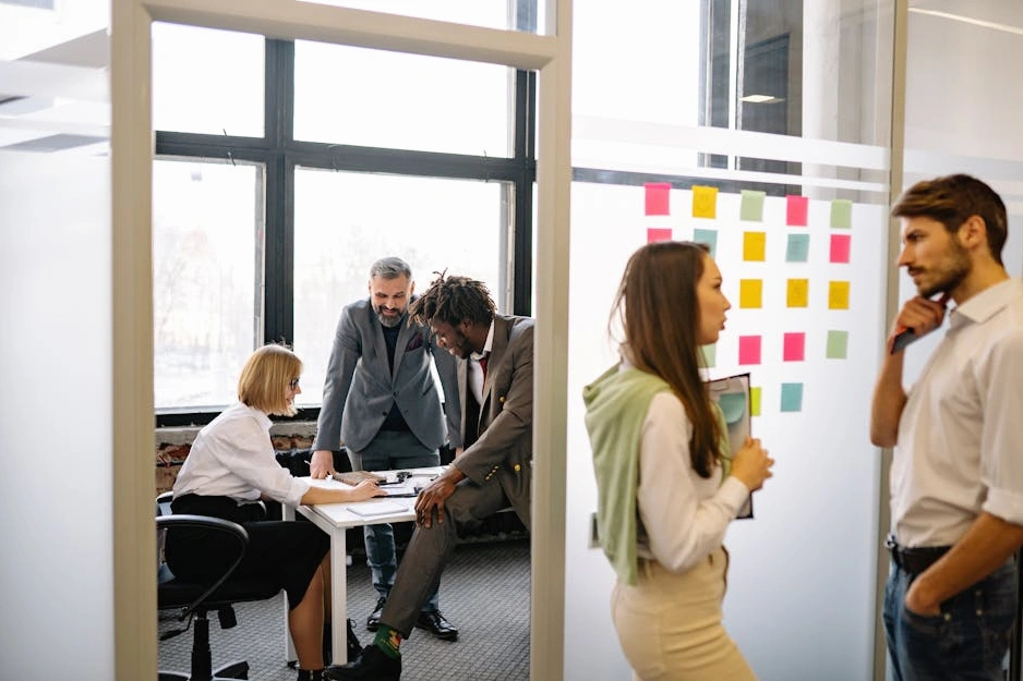 Profesionální tým diskutující strategii v moderní zasedací místnosti, monochromatická fotografie.